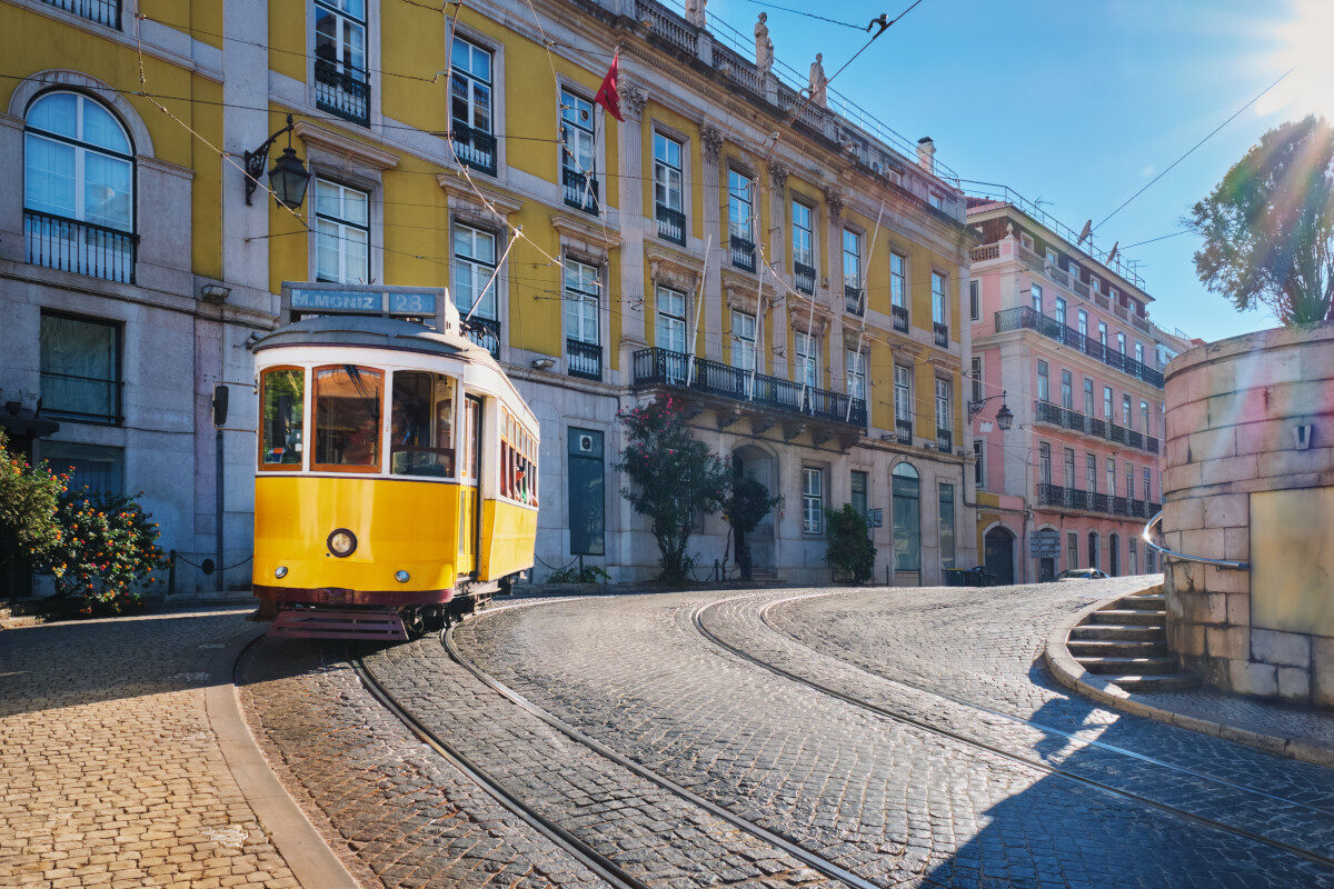 raditional yellow tram passing through a street in Lisbon