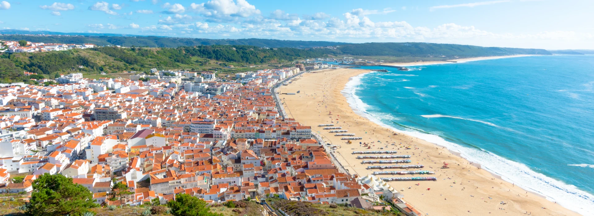 View of Nazaré, Central Portugal — showing the town’s red-tiled roofs and the long Atlantic shoreline.