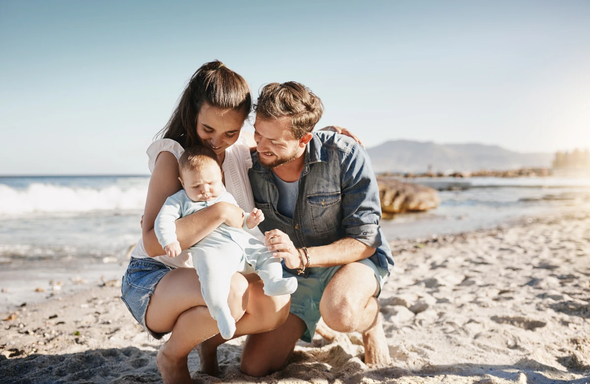 Young family with a baby enjoying time together on a beach in Portugal